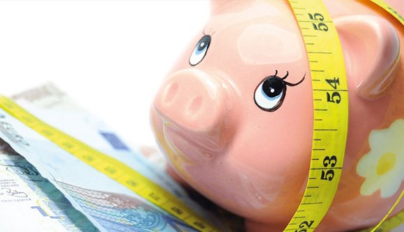 Photo of piggy bank and tape measure representing health and wealth.